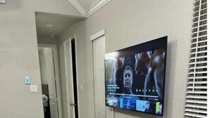Uma sala de estar moderna com uma televisão de tela plana grande na parede, um sofá modular cinza e um tapete estampado.