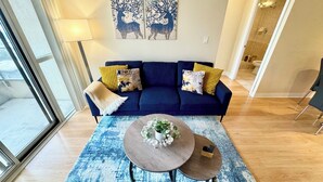A living room with a blue sofa, yellow cushions, a round coffee table with a plant, and two wall art pieces of deer.