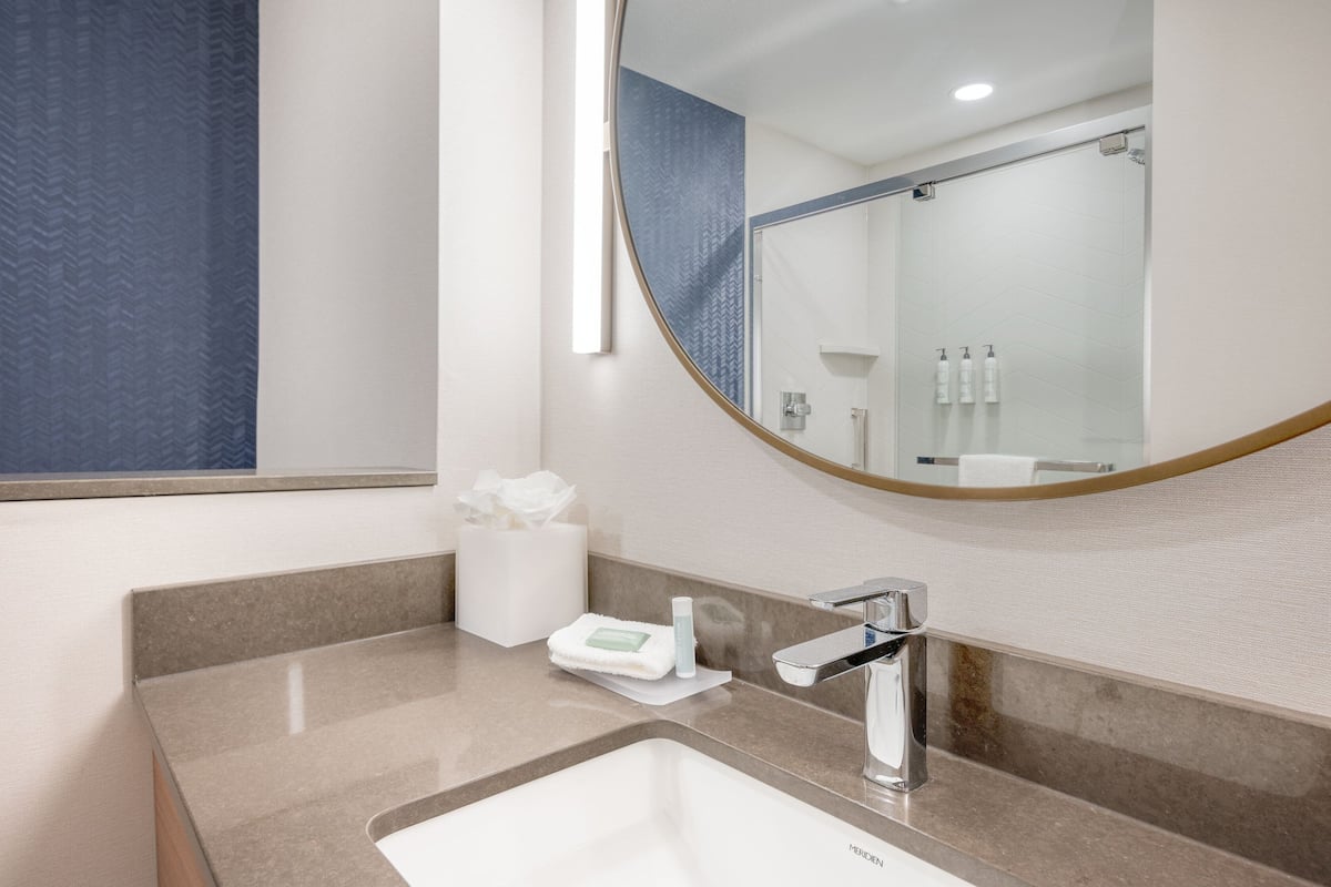 Un baño moderno con un espejo grande, un lavabo y artículos de aseo.