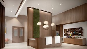 A modern reception area with a wooden reception desk, a green vertical garden, and pendant lighting. - Element by Marriott Charlotte Uptown (Charlotte)