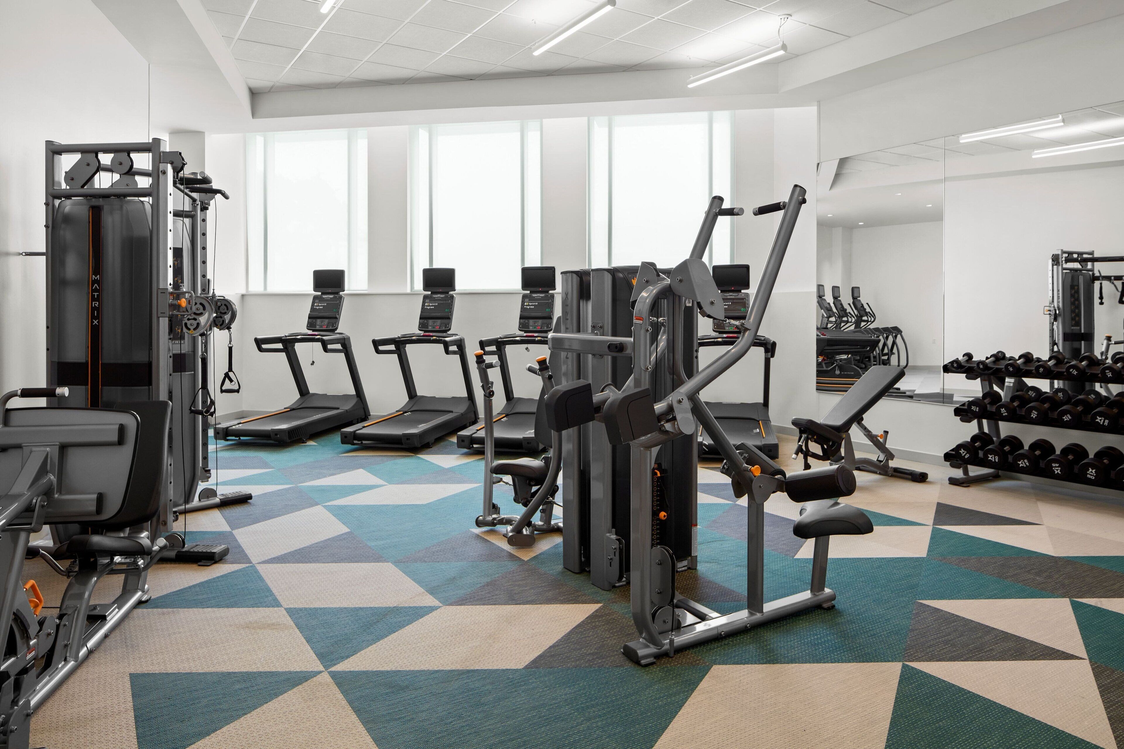 Academia com diversos equipamentos de exercício, incluindo esteiras, aparelhos de musculação e halteres.