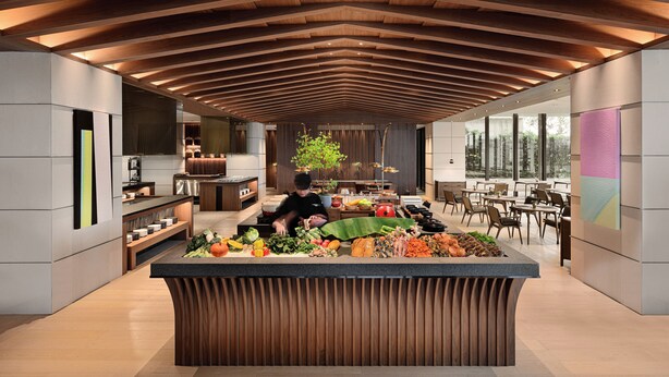 Una cocina moderna con una isla central, techo de madera y ventanas amplias.