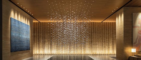 A spacious lobby with a large, reflective floor, a prominent blue artwork on the left, and a patterned wall on the right.