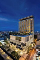 Un hotel moderno con una fachada de vidrio llamativa, varios pisos y una terraza en la azotea.