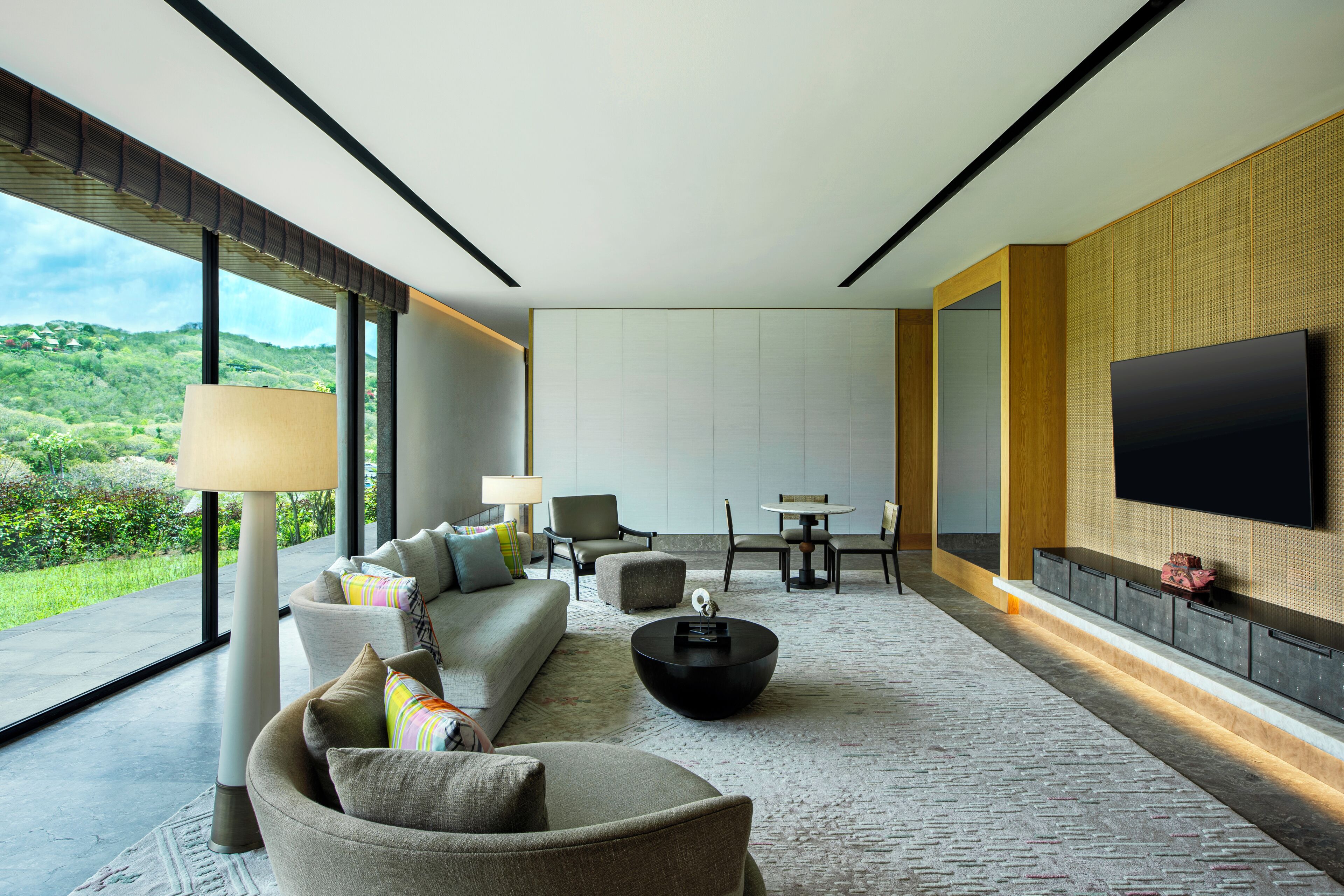 A modern living room with a sofa, chairs, a coffee table, and a TV mounted on the wall.