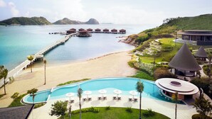 Un complexe hôtelier doté d’une piscine, d’une plage et de bungalows sur pilotis.
