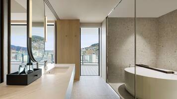 A modern bathroom with a large bathtub, a glass shower enclosure, and a view of a cityscape.