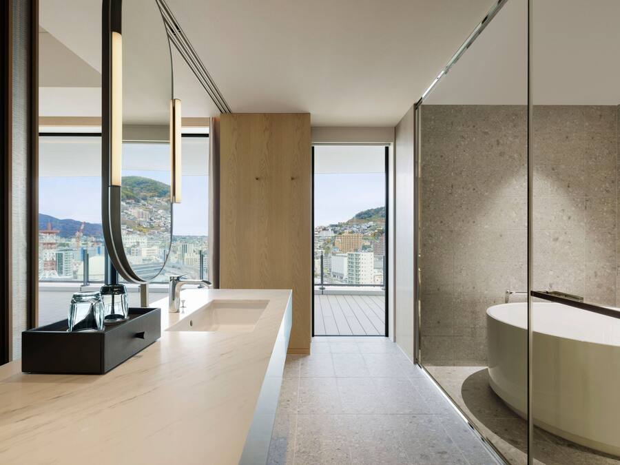 A modern bathroom with a large bathtub, a glass shower enclosure, and a view of a cityscape.