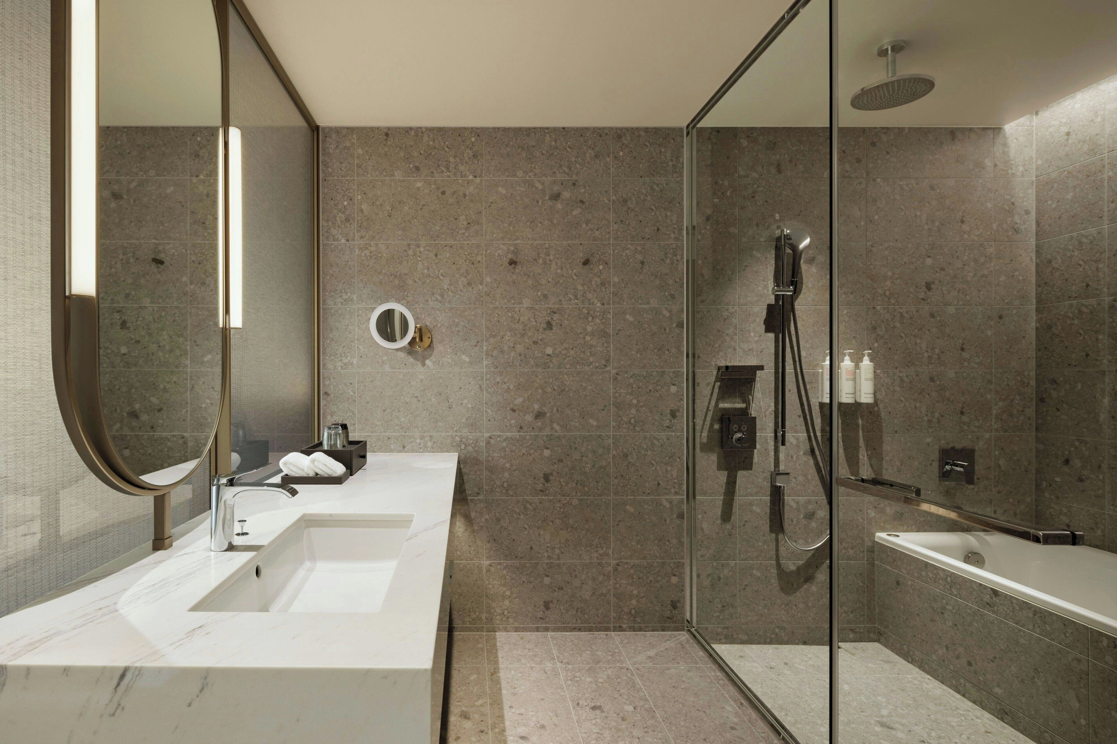 A modern bathroom with a glass-enclosed shower, two sinks, and a large mirror.