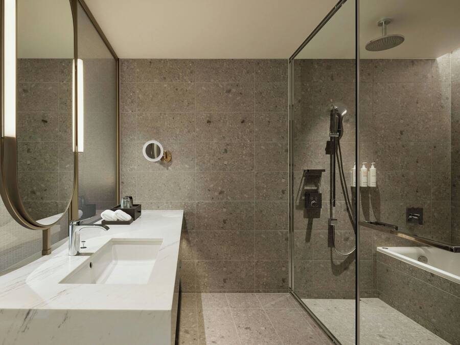A modern bathroom with a glass-enclosed shower, two sinks, and a large mirror.