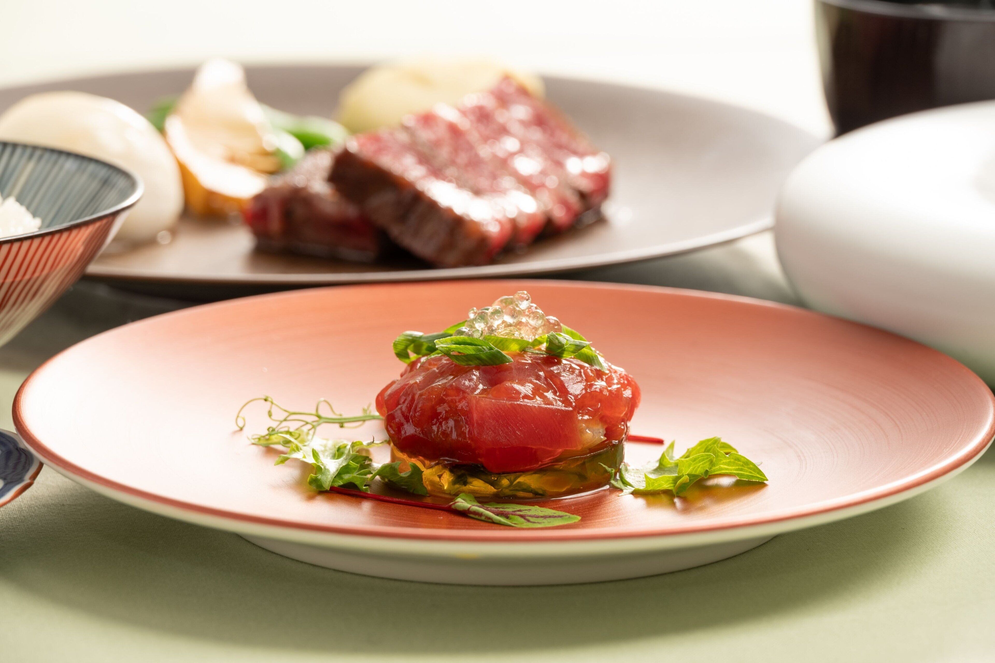 A plate of food with a red center, possibly a tartare, on a pink plate.