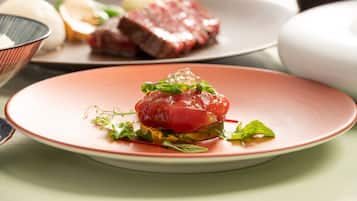 A plate of food with a red center, possibly a tartare, on a pink plate.