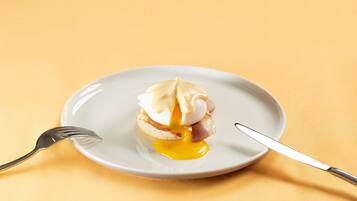 A plate with a poached egg on toast and a fork and knife beside it.