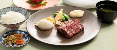 A table with various dishes including a plate of meat, vegetables, and rice.