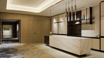 A modern kitchen with a marble countertop, wooden cabinets, and pendant lighting.