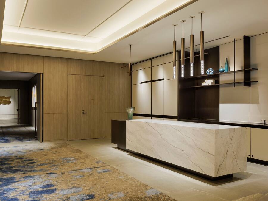A modern kitchen with a marble countertop, wooden cabinets, and pendant lighting.