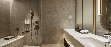 A modern bathroom with a glass-enclosed shower, a large mirror, and a vanity with a sink and towel rack.