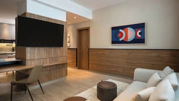 Un soggiorno moderno con un divano, un tavolino, una TV montata su un pannello di legno e un quadro appeso al muro.