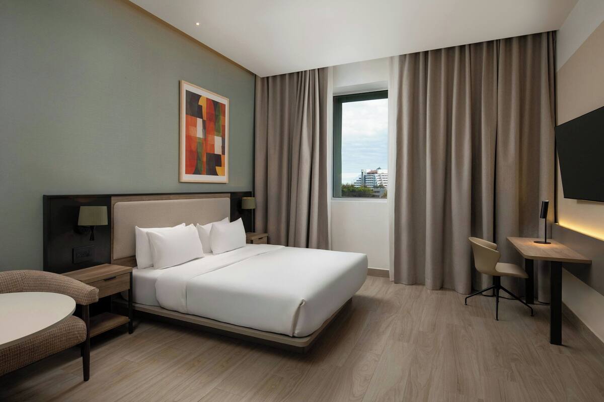 Une chambre d’hôtel moderne équipée d’un grand lit, d’un bureau, d’une chaise et d’un téléviseur.