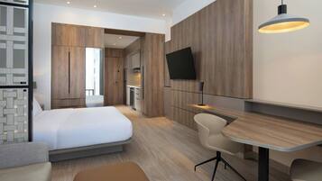 Een moderne hotelkamer met een bed, een bureau, een stoel en een aan de muur bevestigde televisie.
