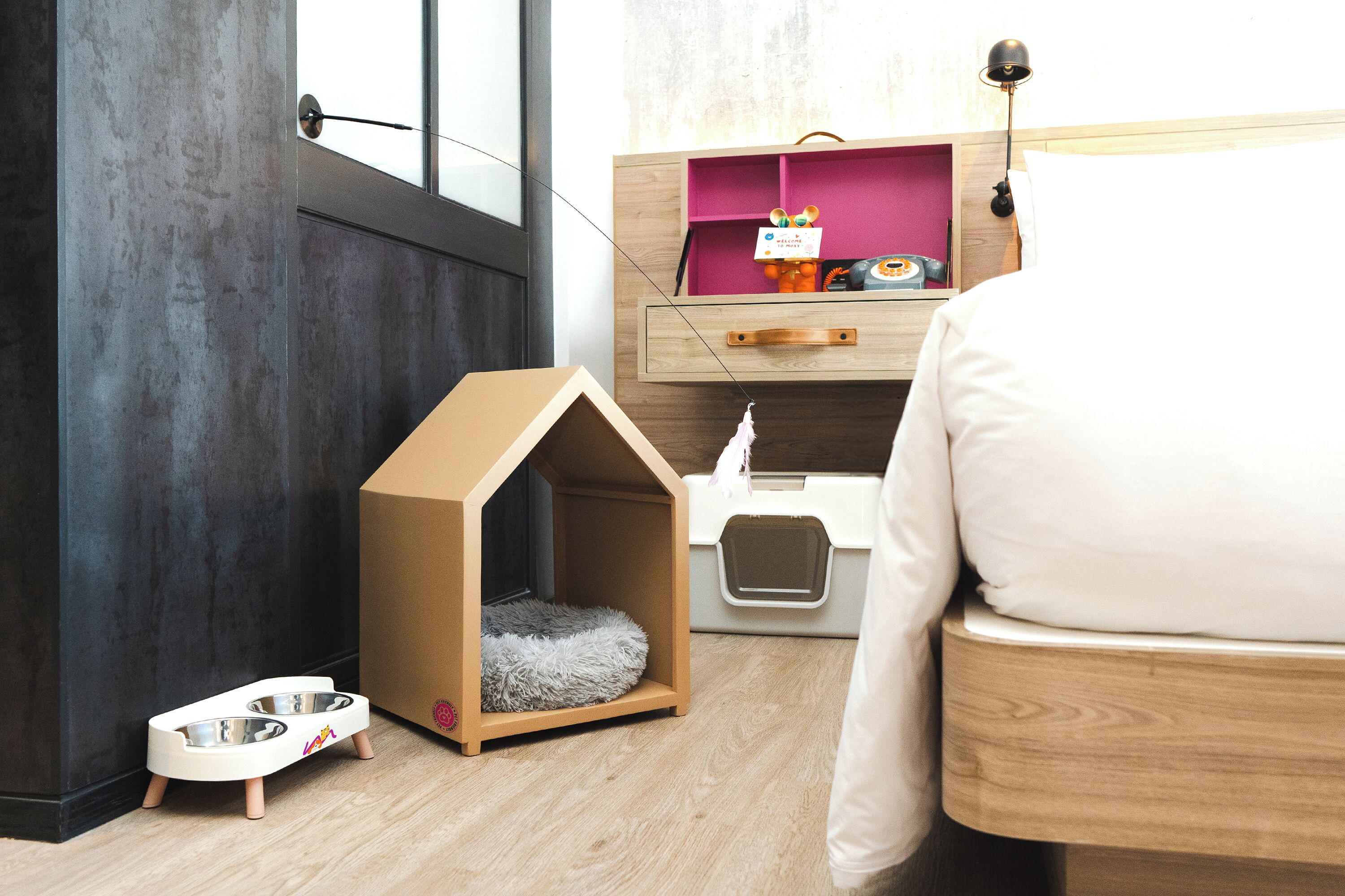 A pet-friendly room with a wooden bed, a pet house, a litter box, and a pet bowl.
