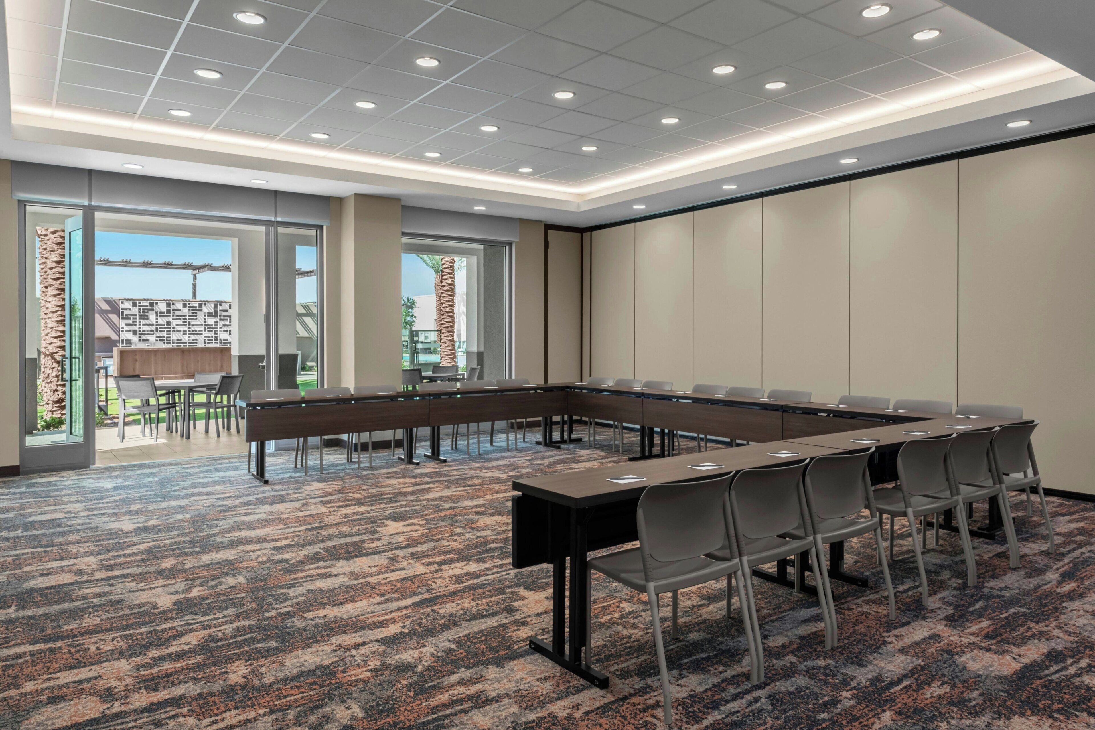 A conference room with a long table, chairs, and a carpeted floor.