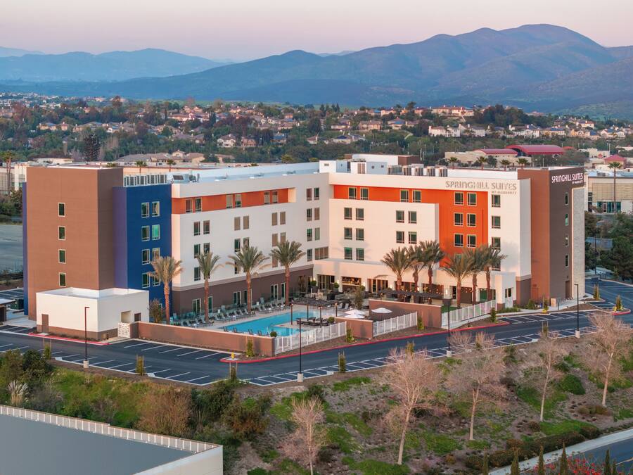 A hotel with a swimming pool, multiple floors, and a view of the surrounding area.