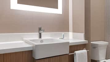 A modern bathroom with a large mirror, a sink, and a toilet.