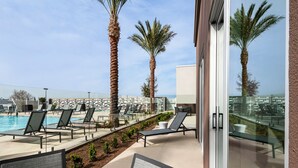 A poolside area with lounge chairs and palm trees, overlooking a body of water. - SpringHill Suites by Marriott Chula Vista Eastlake (Chula Vista)