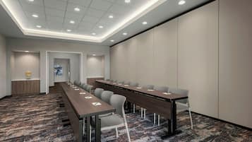 Un salón de conferencias con una larga mesa, sillas y suelo alfombrado.