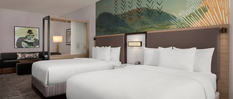 Habitación de hotel con dos camas, un sofá, un cuadro y una lámpara.