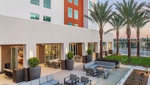 A modern outdoor lounge area with seating, a fire pit, and palm trees. - SpringHill Suites by Marriott Chula Vista Eastlake (Chula Vista)