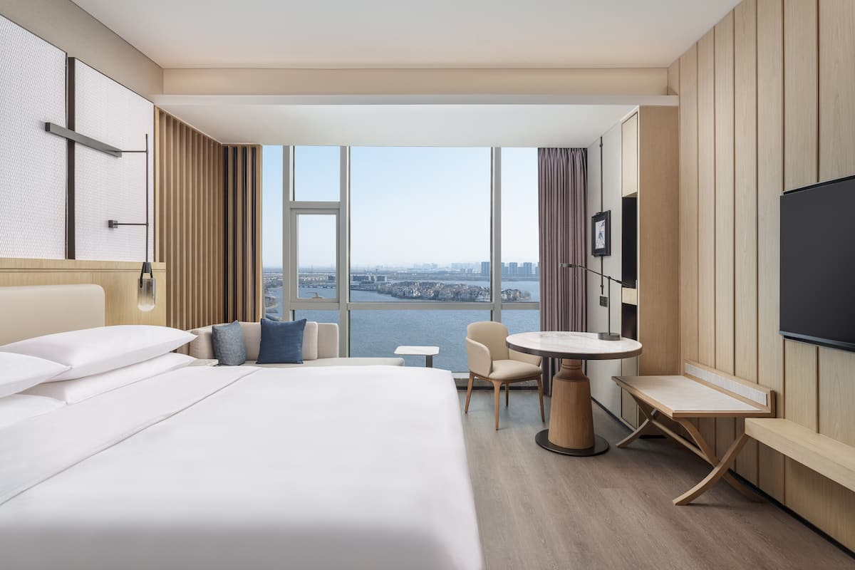Una habitación de hotel con una cama grande, un escritorio, una silla y un televisor.
