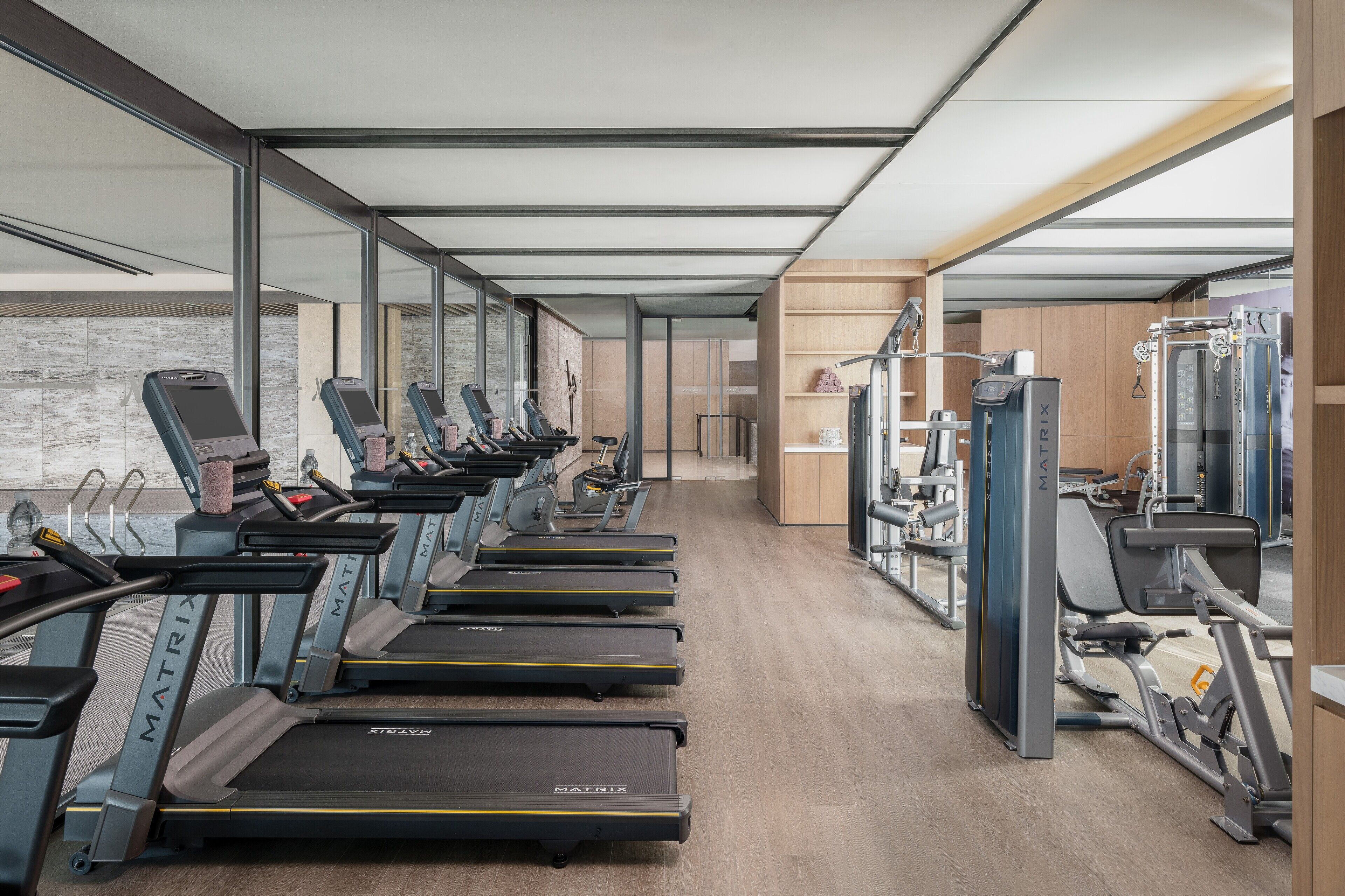 A modern gym with treadmills, weight machines, and a mirrored wall.