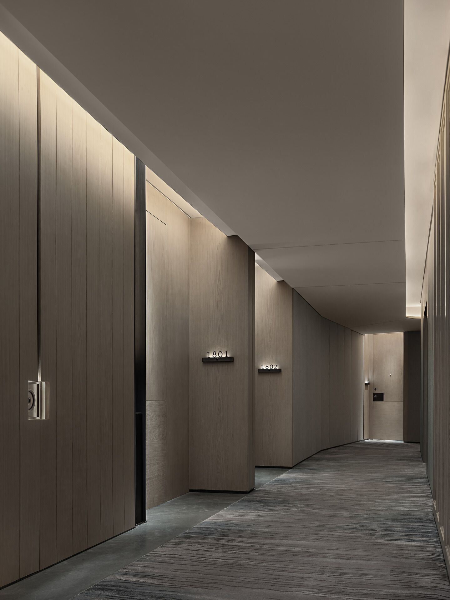 A modern hallway with wooden paneling and numbered doors.
