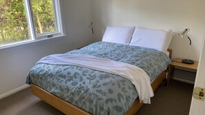 A bedroom with a bed, a nightstand, a lamp, and a window.