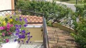 Ein Balkon mit Blick auf einen Garten und eine Straße.