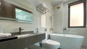 A modern bathroom with a freestanding bathtub, a toilet, and a vanity with a mirror.
