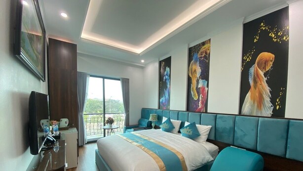A modern hotel room with a large bed, a seating area, and artwork on the walls.