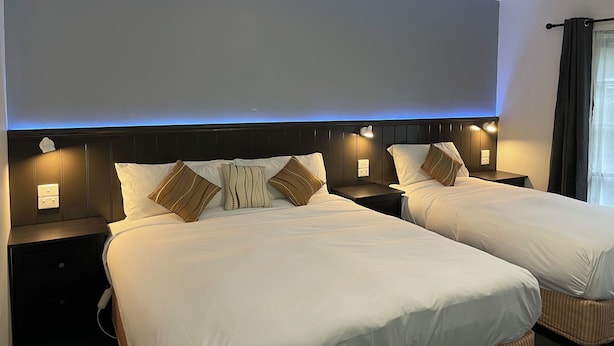 A hotel room with two beds, each with white bedding and decorative pillows. There are bedside tables with lamps and a wall-mounted light. - COUNTRY PLAZA HALLS GAP (Halls Gap)