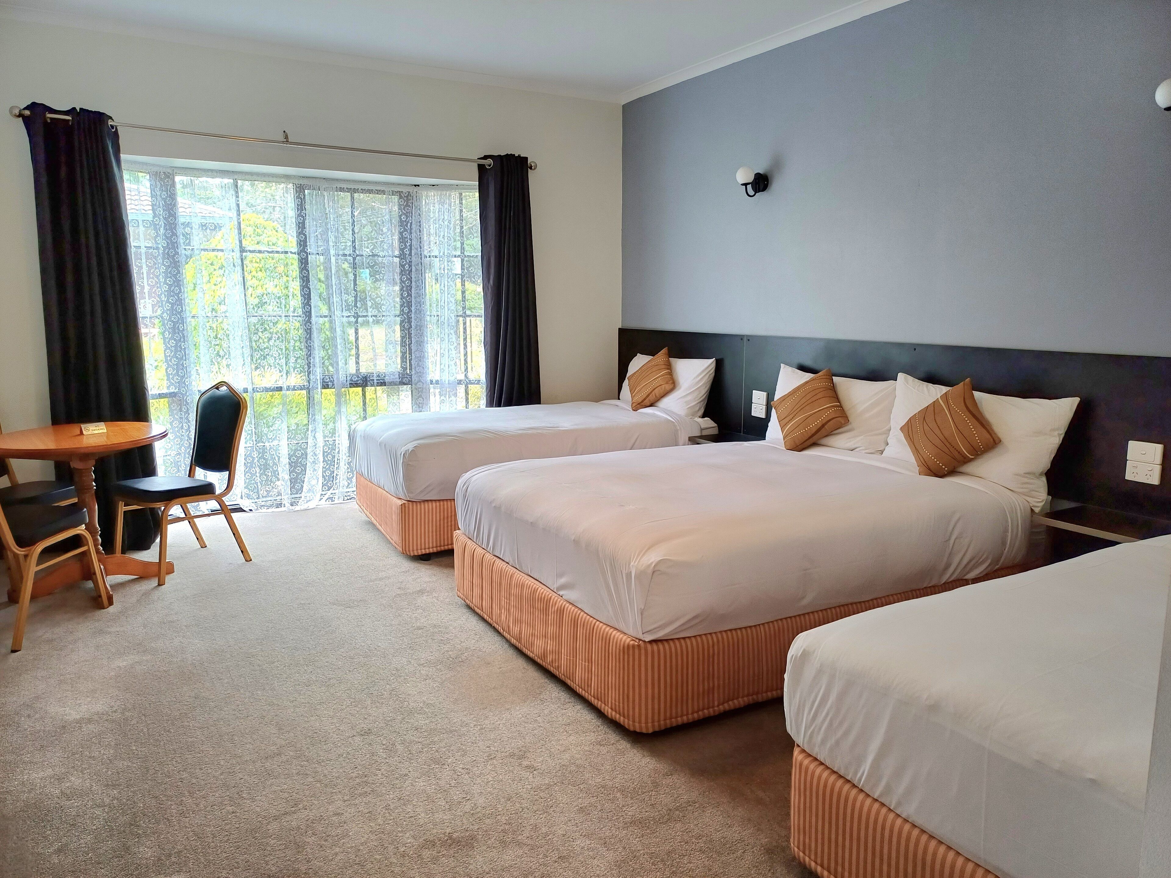 Une chambre d’hôtel avec deux lits, un bureau et une chaise.