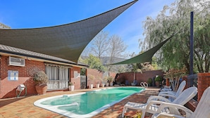 A swimming pool with lounge chairs, a shaded area, and a brick patio. - COUNTRY PLAZA HALLS GAP (Halls Gap)