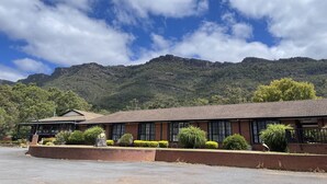 A two-story building with a tiled roof, surrounded by landscaped greenery and a mountain backdrop. - COUNTRY PLAZA HALLS GAP (Halls Gap)