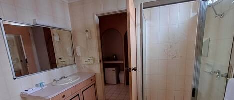 A bathroom with a sink, mirror, and shower.
