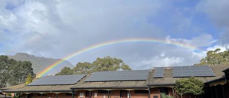A building with solar panels, a parking area, and a mountain backdrop.