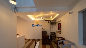 A hallway with a striped floor, a ceiling with recessed lighting, a sign reading "Bonne Chance," and a small wooden cabinet.