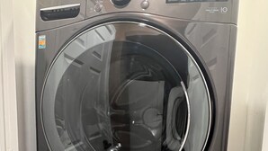 A front view of a modern LG washing machine with a digital display, control panel, and a transparent door.