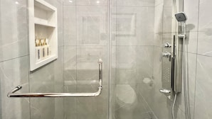 A modern shower with a handheld showerhead, a glass-enclosed shower stall, and a grab bar.