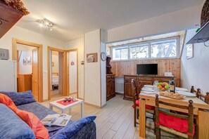 Un salon confortable avec un canapé, une table à manger pour quatre personnes et une cuisine dotée de meubles en bois et d’un téléviseur.