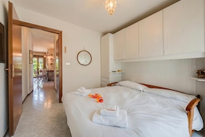 A hotel room with a bed, a wooden headboard, a mirror, and a view of a dining area.